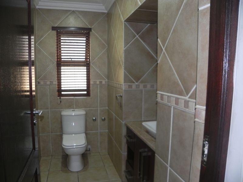 A compact bathroom featuring floor-to-ceiling tiled walls, a built-in vanity with a vessel sink, and a standard toilet.