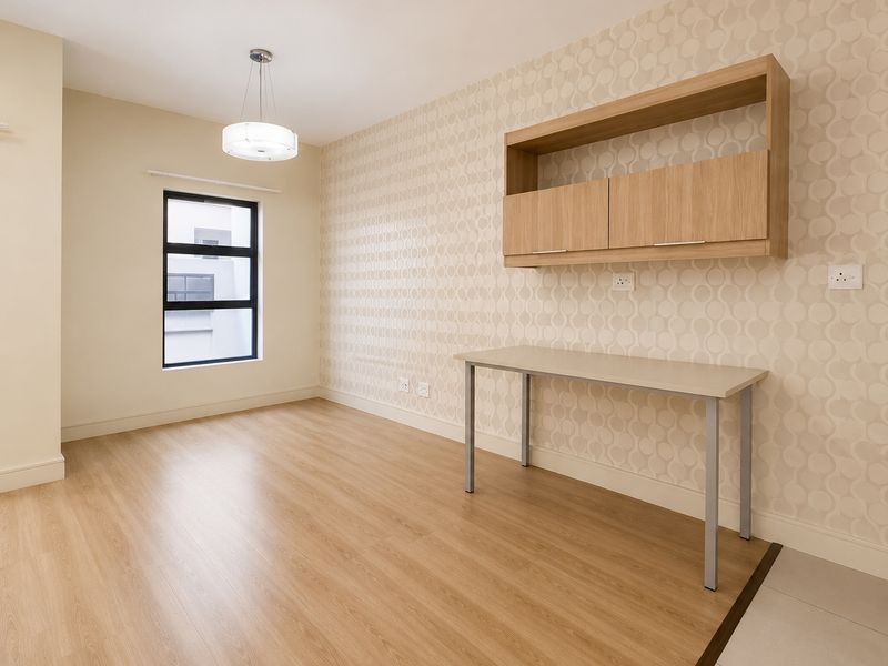 A bright, modern bedroom or office space featuring wood-look laminate flooring, patterned wallpaper, and built-in wall-mounted cabinetry.