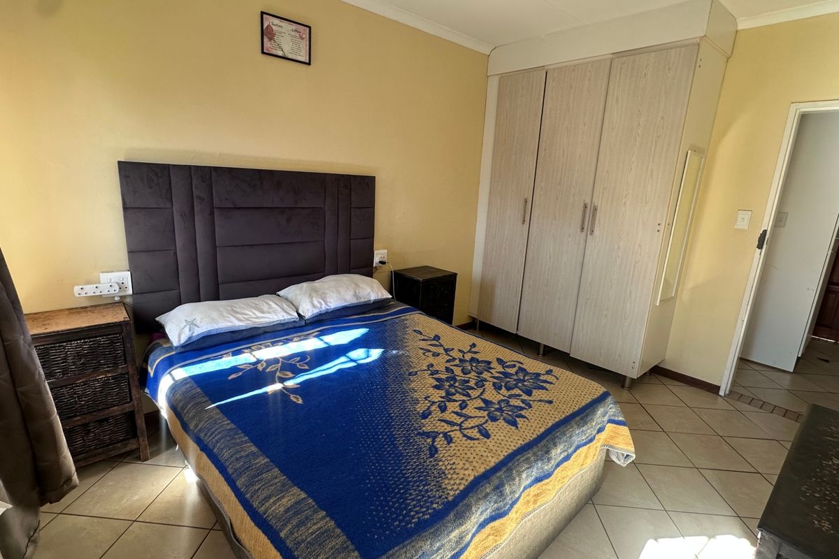A functional bedroom featuring tiled flooring, a built-in wardrobe, and coved ceiling details, providing a practical living space.