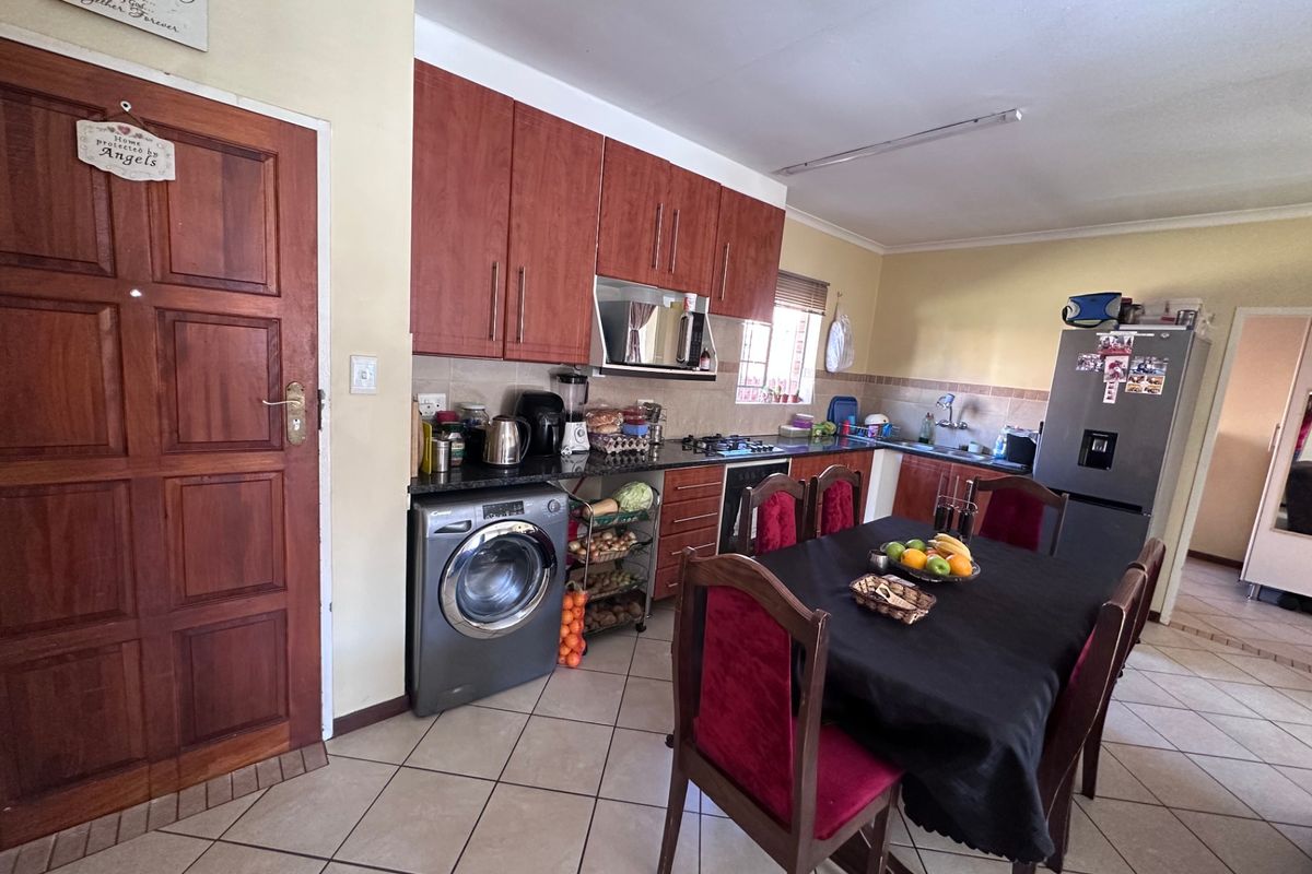 Functional kitchen featuring wooden cabinetry, granite countertops, built-in oven, hob, and tiled flooring, with an integrated laundry area.
