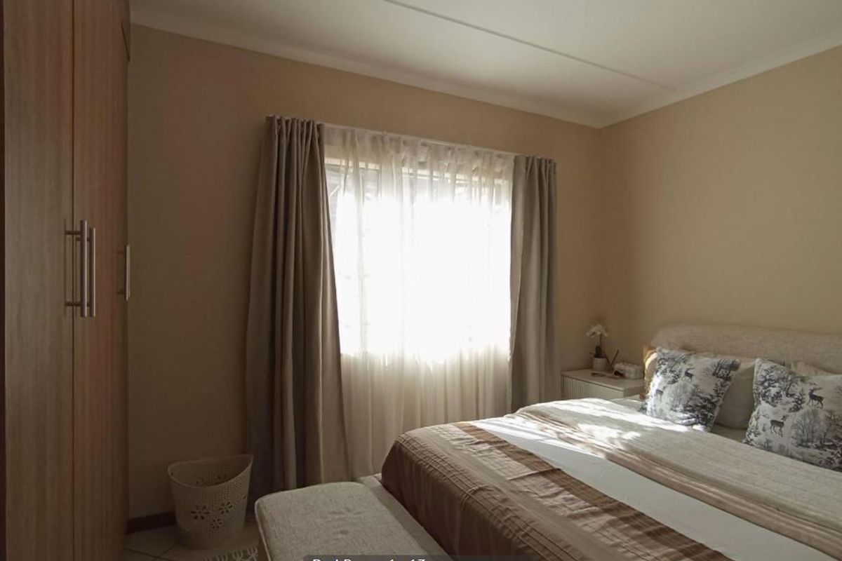 A functional bedroom featuring built-in wardrobes and tiled flooring, offering a neutral palette and natural light.
