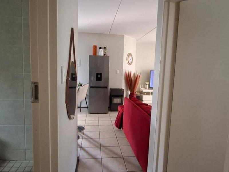 A view from a hallway looking into an open-plan living and kitchen area, featuring tiled flooring throughout the transition space.