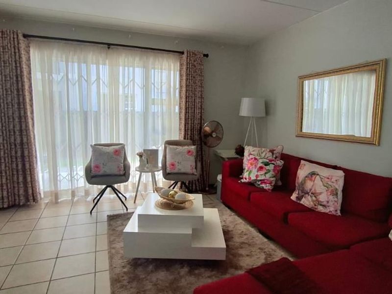 A comfortable living room featuring tiled flooring and a large sliding glass door with a security gate, providing access to the outdoor area.