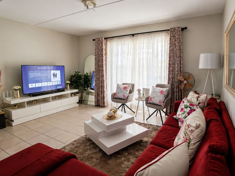 A well-maintained living room featuring neutral tiled flooring and a large sliding glass door that provides ample natural light.