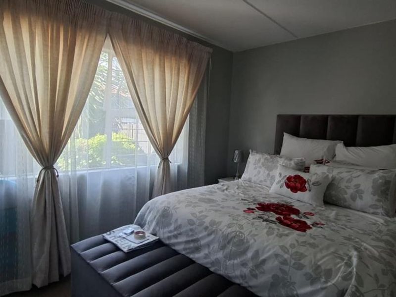 A cozy bedroom featuring a built-in wardrobe and a large window that allows natural light into the space.