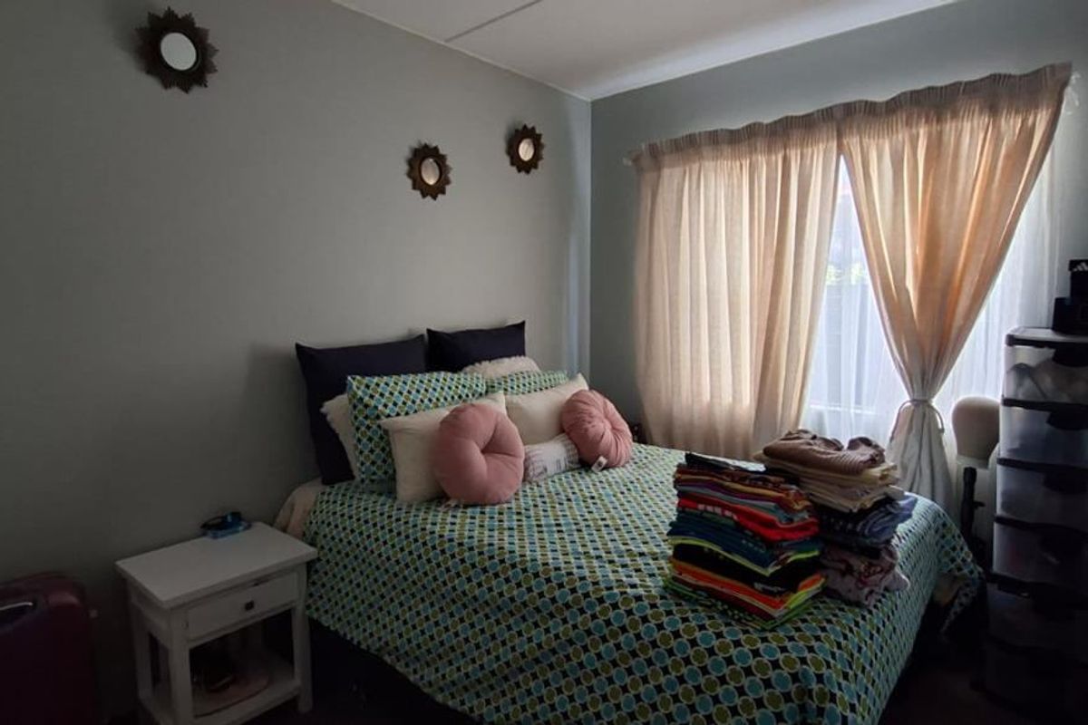 A functional bedroom featuring a built-in wardrobe and natural light through a window with curtains.