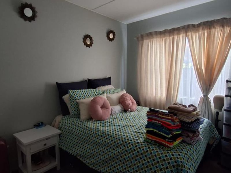 A functional bedroom featuring a built-in wardrobe and natural light through a window with curtains.