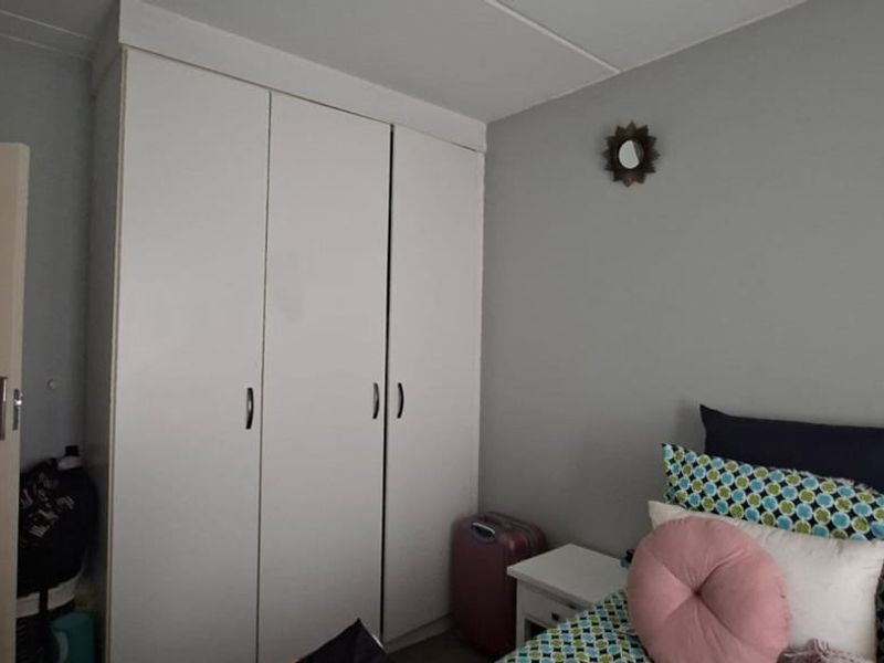 A bedroom featuring a white built-in wardrobe with ample storage space.