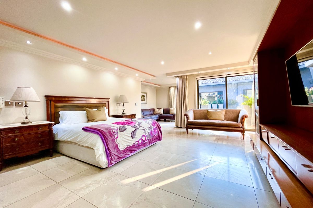 Spacious bedroom featuring large format floor tiles, recessed ceiling lighting, and sliding glass doors providing access to the outdoor area.