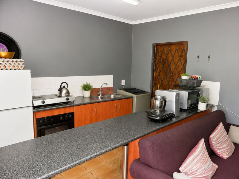 Compact open-plan kitchen featuring laminate countertops, built-in oven, hob, and double sink, seamlessly integrated with the living area.