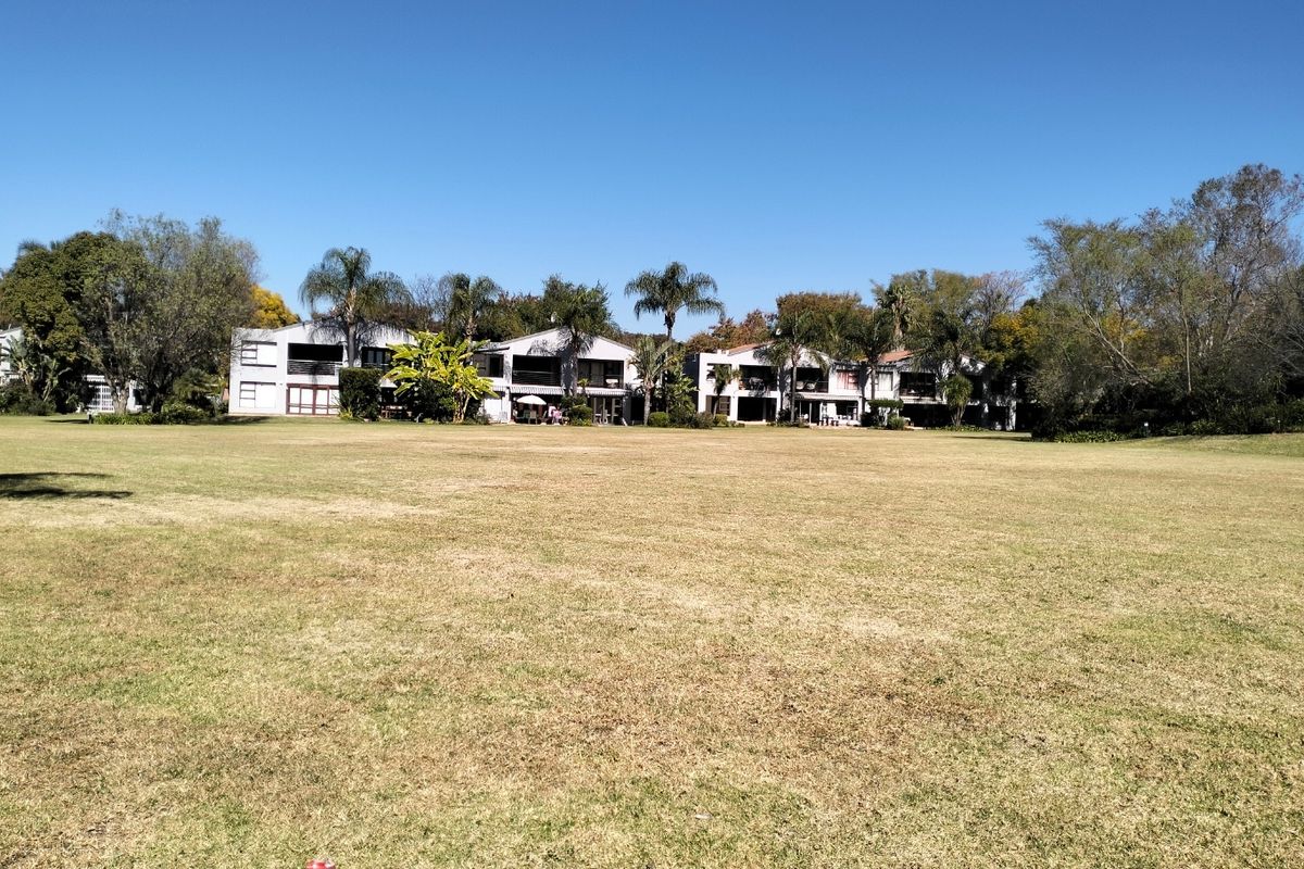 A wide-angle view of the townhouse complex exterior, showcasing the rear building facades and the expansive communal lawn area.