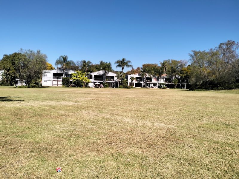 A wide-angle view of the townhouse complex exterior, showcasing the rear building facades and the expansive communal lawn area.