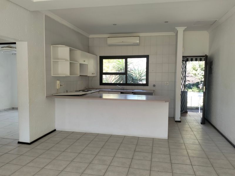 A functional kitchen featuring a breakfast bar, built-in cabinetry, and tiled flooring, offering a clean and open layout ready for updates.
