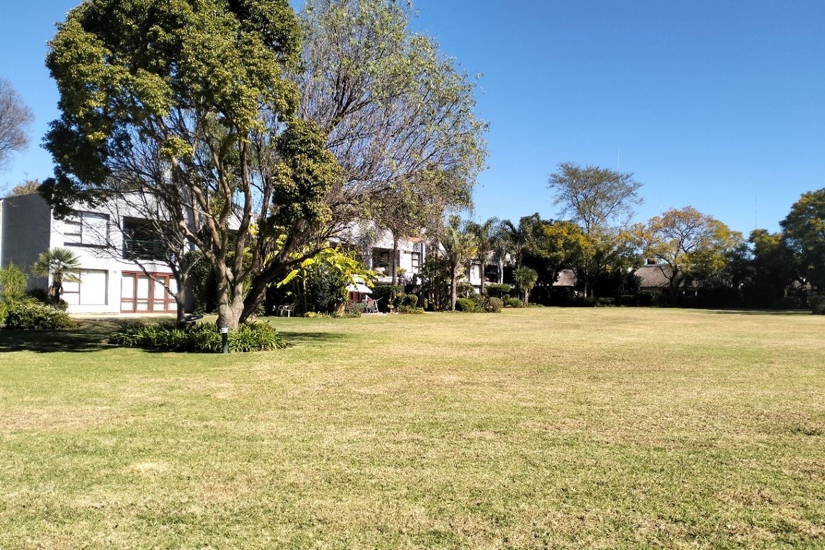 A view of the expansive communal garden area featuring mature trees and well-maintained lawn, providing a pleasant outdoor space for residents.