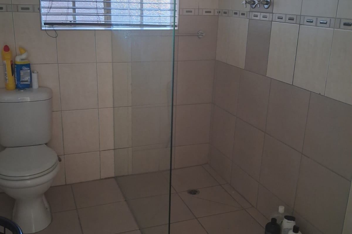 A functional bathroom featuring a walk-in shower with a glass screen, tiled walls, and a standard toilet.