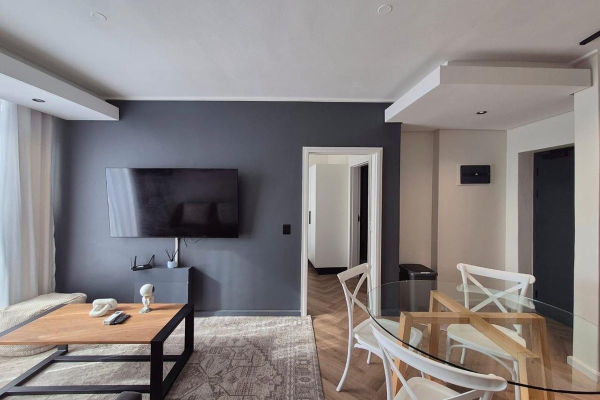 Modern living area featuring dark accent wall, recessed ceiling lighting, and elegant herringbone flooring, creating a contemporary and inviting atmosphere.