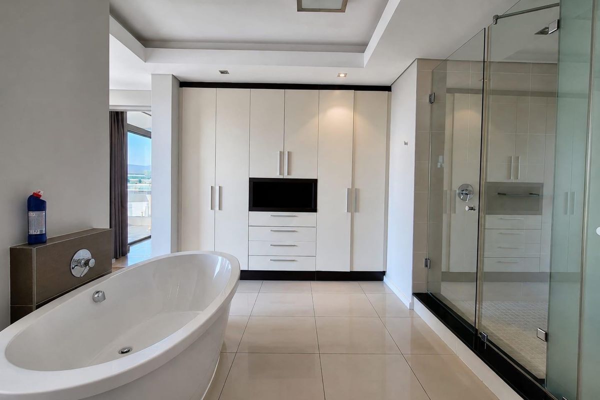 Modern bathroom featuring a sleek freestanding bathtub, a spacious glass-enclosed shower, and extensive built-in cabinetry with integrated storage.