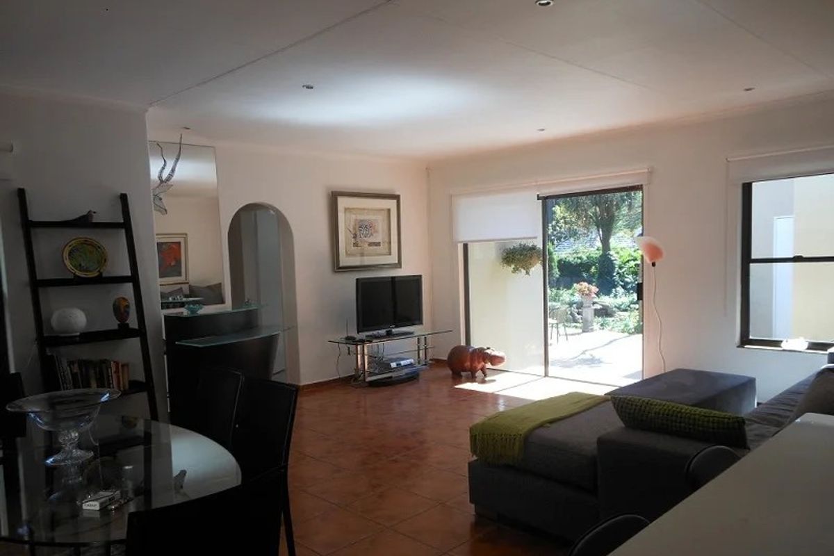 Open plan living area featuring terracotta floor tiles, recessed downlighting, and large sliding glass doors providing direct access to the rear patio and garden.