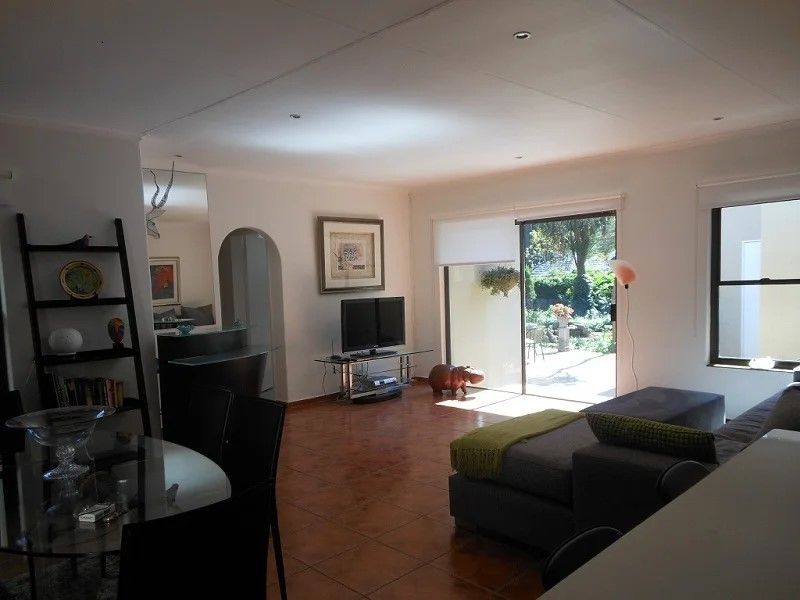 Open plan living area featuring terracotta floor tiles, recessed downlighting, and large sliding glass doors providing direct access to the rear patio and garden.