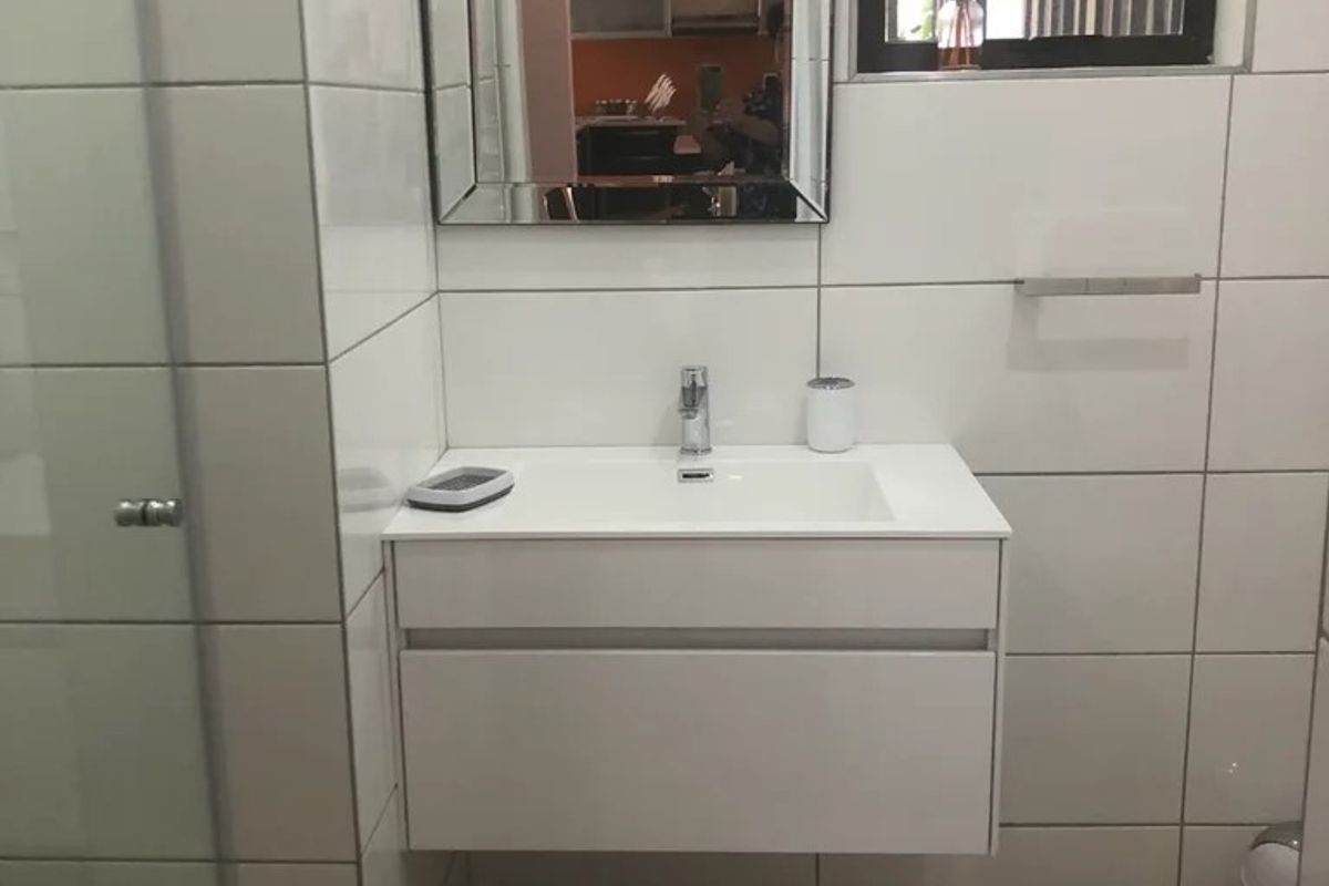 A modern bathroom featuring a wall-mounted vanity with a white basin, large format wall tiles, and a framed mirror.