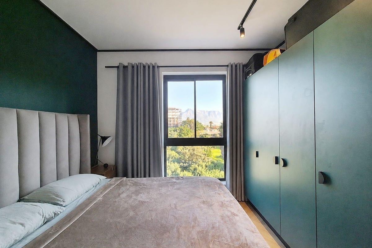 Modern bedroom featuring a large built-in wardrobe, track lighting, and a window with scenic mountain views.