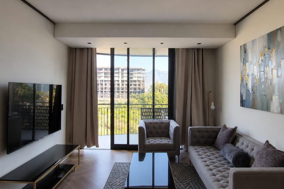 Modern living room featuring herringbone timber flooring, recessed ceiling lighting, and large sliding glass doors opening to a balcony with scenic views.