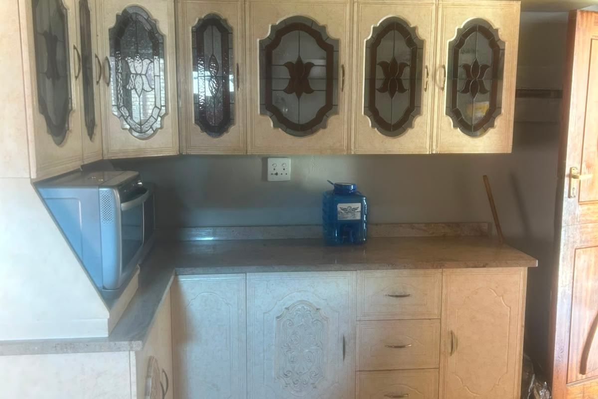 A kitchen area featuring traditional cabinetry with decorative glass inserts, stone-look countertops, and tiled flooring.