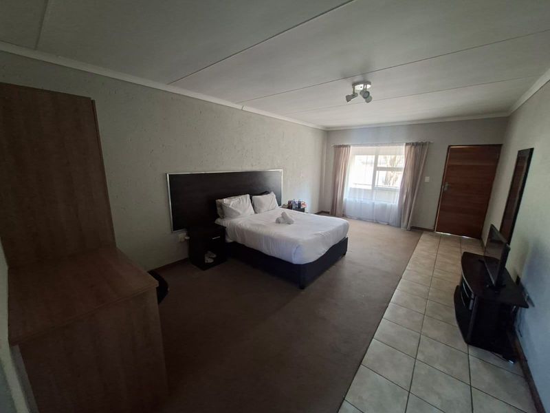 Spacious bedroom featuring a combination of carpet and tiled flooring, neutral wall finishes, and a large window allowing for natural light.