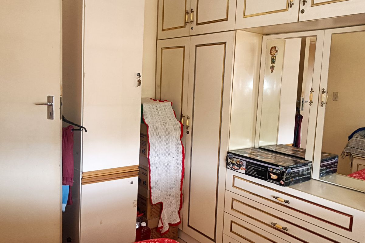Bedroom featuring extensive built-in cabinetry with integrated vanity mirror and storage drawers, showing signs of age and wear.