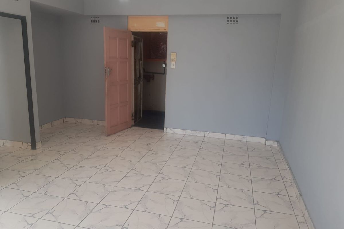 An empty living area featuring light-colored floor tiles and neutral grey walls, providing a blank canvas for personalization.