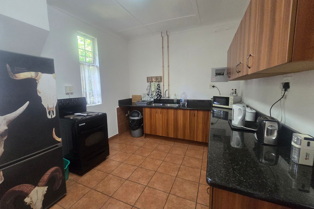 Functional kitchen featuring granite countertops, wood-look cabinetry, and ceramic tile flooring, with exposed plumbing and a standard layout.