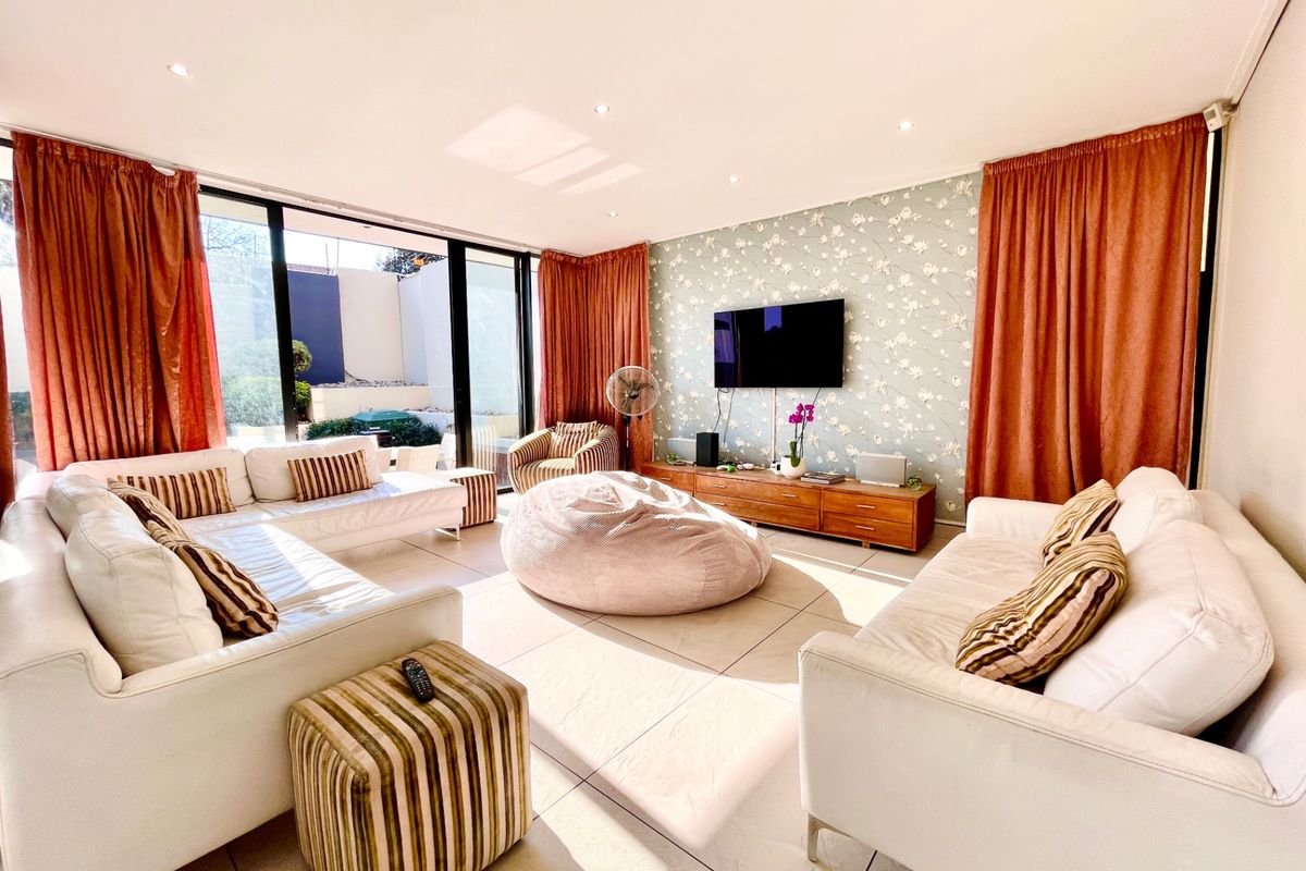 Spacious living room featuring large sliding glass doors, tiled flooring, recessed lighting, and a decorative wallpaper feature wall.