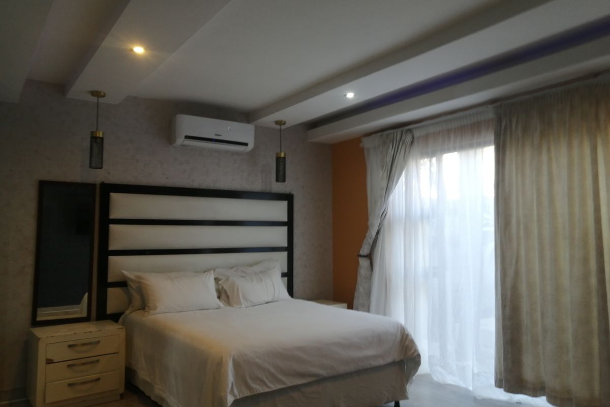 A well-lit bedroom featuring a recessed ceiling, split-system air conditioning, and sliding glass doors leading to an outdoor area.