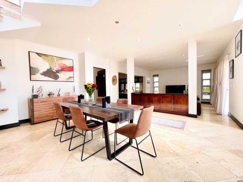 Spacious open-plan living and dining area featuring polished travertine flooring, recessed lighting, and neutral walls, creating a bright and airy atmosphere.