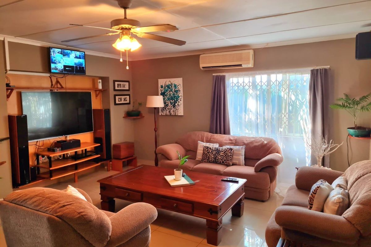 A comfortable living room featuring tiled flooring, a ceiling fan, and a wall-mounted air conditioning unit, providing a functional and well-lit space.