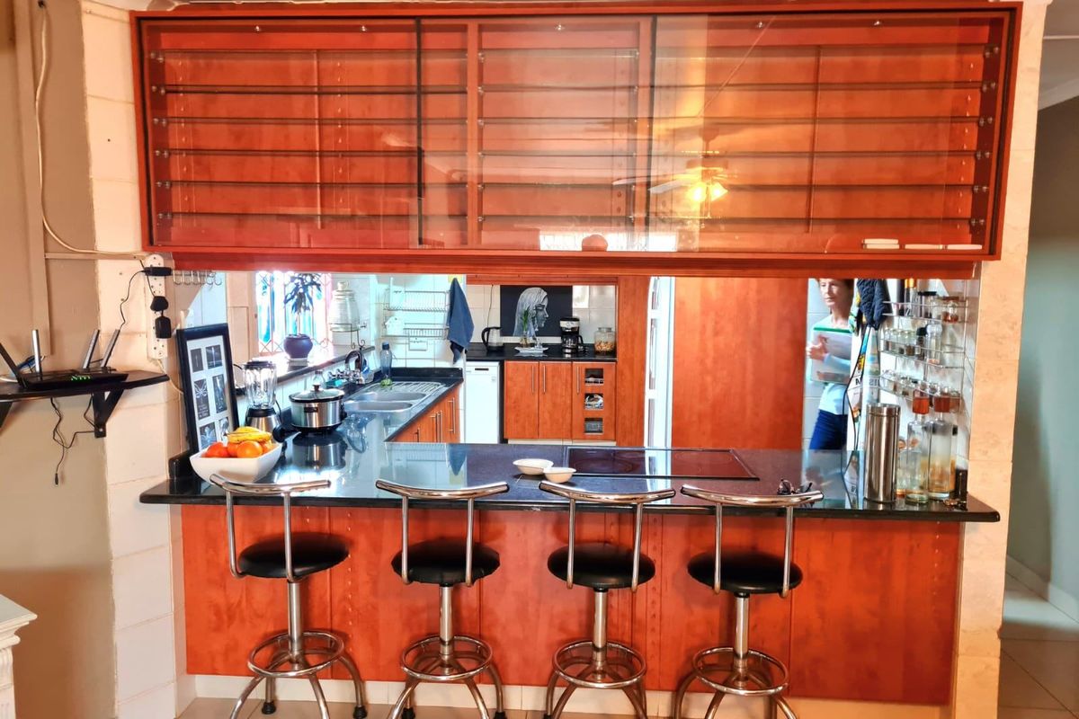A functional kitchen featuring warm-toned wooden cabinetry, a black granite breakfast bar, and integrated cooktop, offering a practical layout for cooking and casual dining.