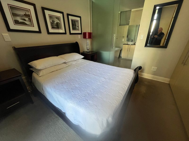 A well-maintained bedroom featuring built-in cupboards and an en-suite bathroom separated by a modern frosted glass partition.