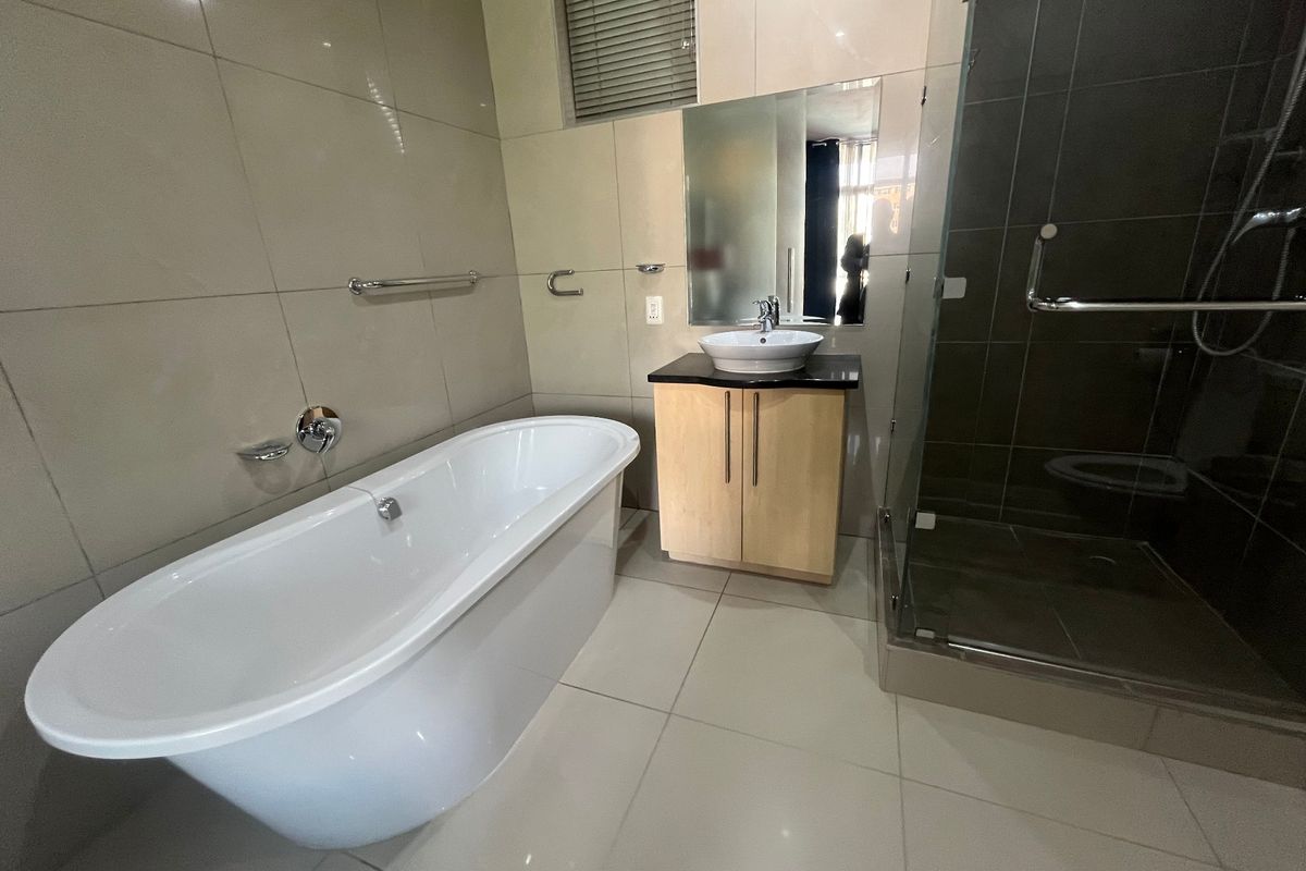 Modern bathroom featuring a freestanding bathtub, a glass-enclosed shower, and a vanity with a vessel sink, finished with neutral wall and floor tiles.