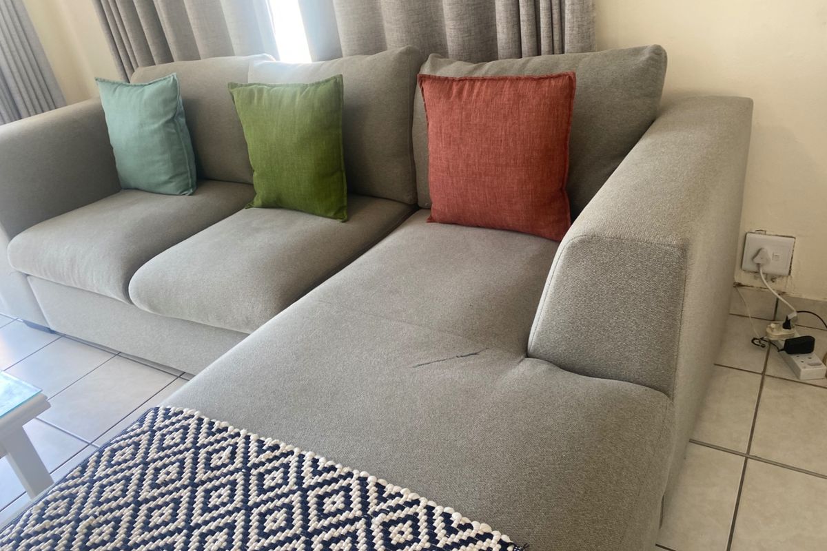 A living room area featuring neutral tiled flooring and standard electrical wall outlets.