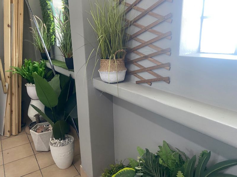 A corner area featuring tiled flooring and a built-in ledge, currently decorated with various potted plants and decorative wooden lattice.