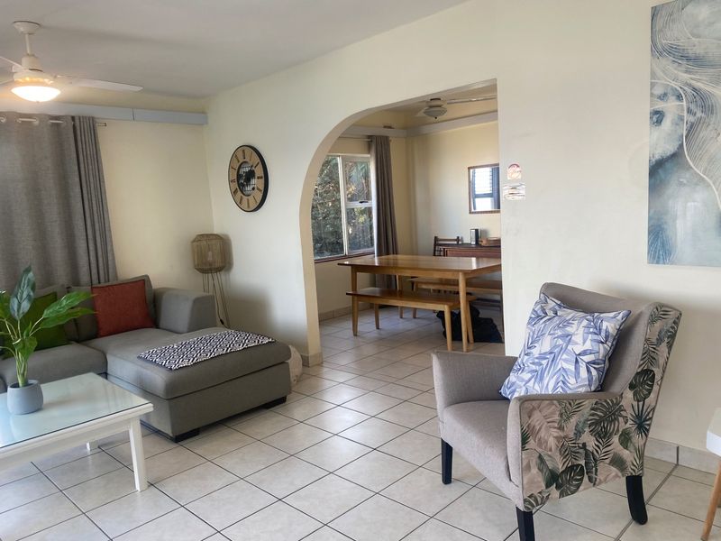 Open-plan living and dining area featuring tiled flooring, a distinctive architectural archway, and ceiling fans, providing a functional and connected living space.