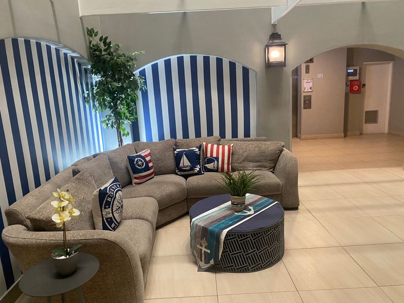 A communal living area featuring arched wall niches with decorative striped wallpaper, tiled flooring, and direct access to the building elevator.