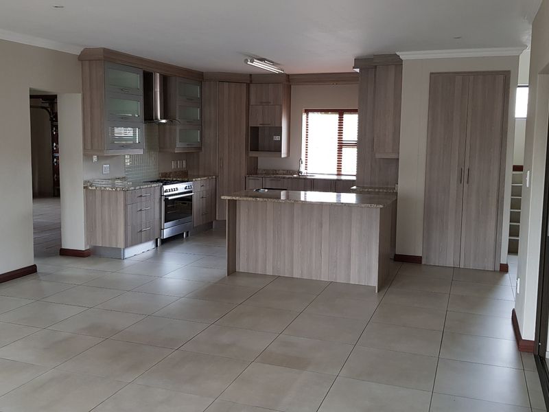 Spacious open-plan kitchen featuring modern wood-finish cabinetry, granite countertops, and a stainless steel gas stove, seamlessly integrated with the living area.