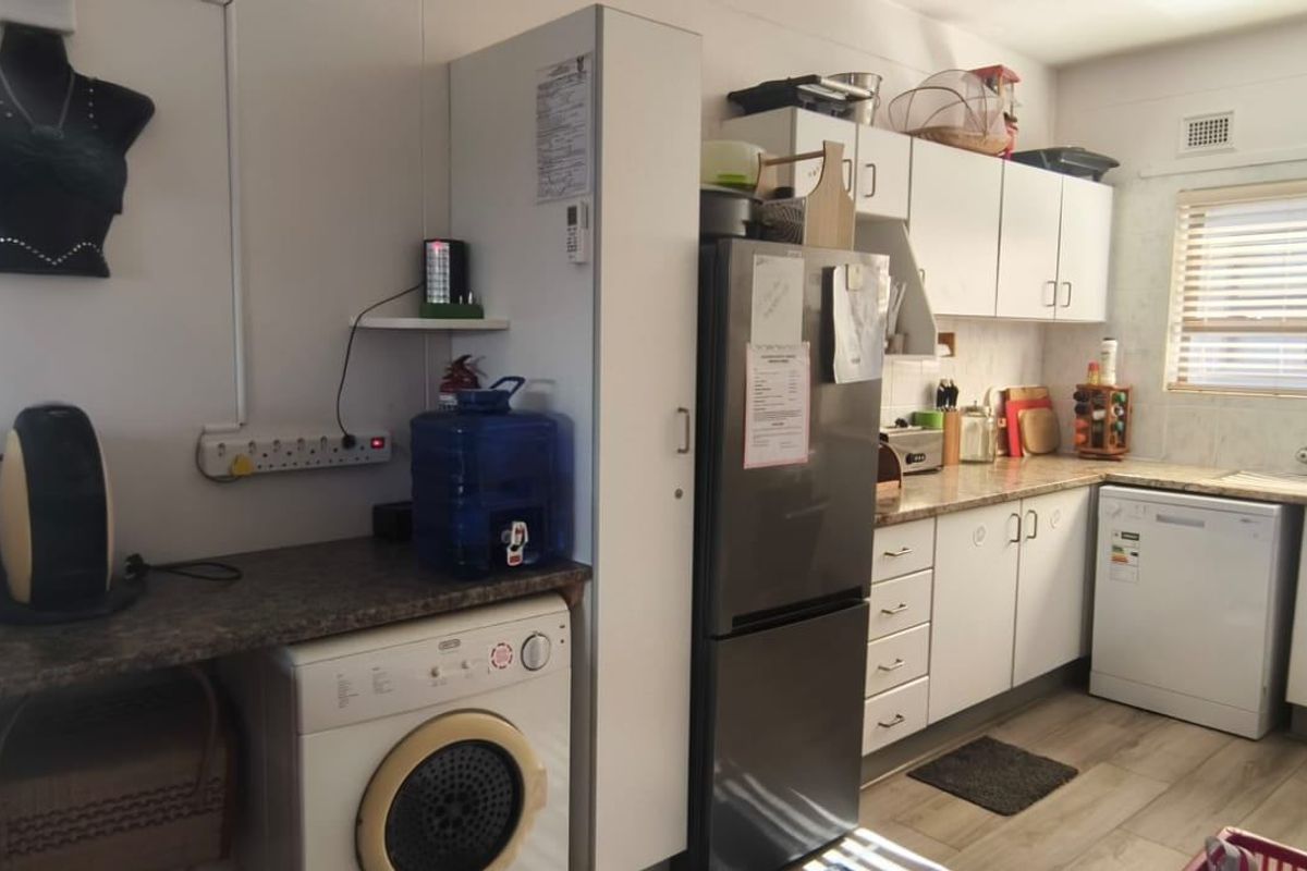 Functional kitchen featuring laminate countertops, ample built-in cabinetry, and tiled flooring, providing a practical workspace for daily meal preparation.