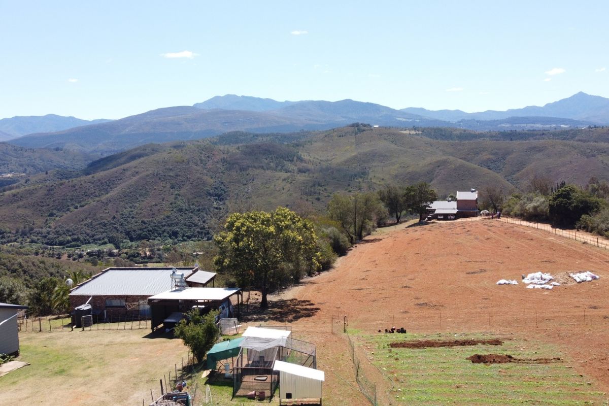 Aerial view of the farm property featuring multiple structures, expansive landscape, mountain views, and agricultural fencing.