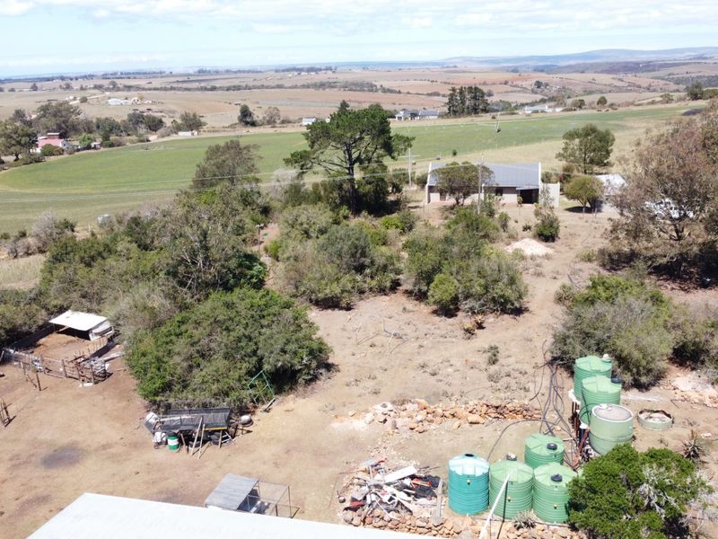Aerial view of a farm property featuring multiple water storage tanks, livestock enclosures, and surrounding agricultural land.