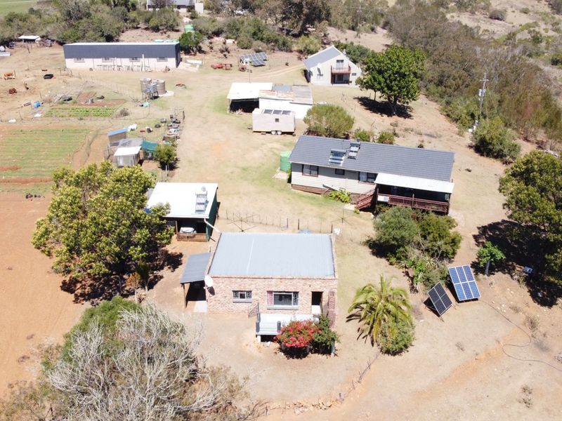 Aerial view of a farm property featuring multiple outbuildings, a main residence, solar panel installations, and established garden areas.