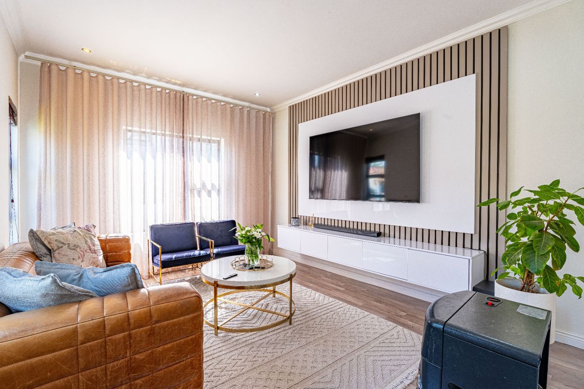 Modern living room featuring a stylish slatted timber feature wall, integrated media console, and high-quality laminate flooring with recessed lighting.