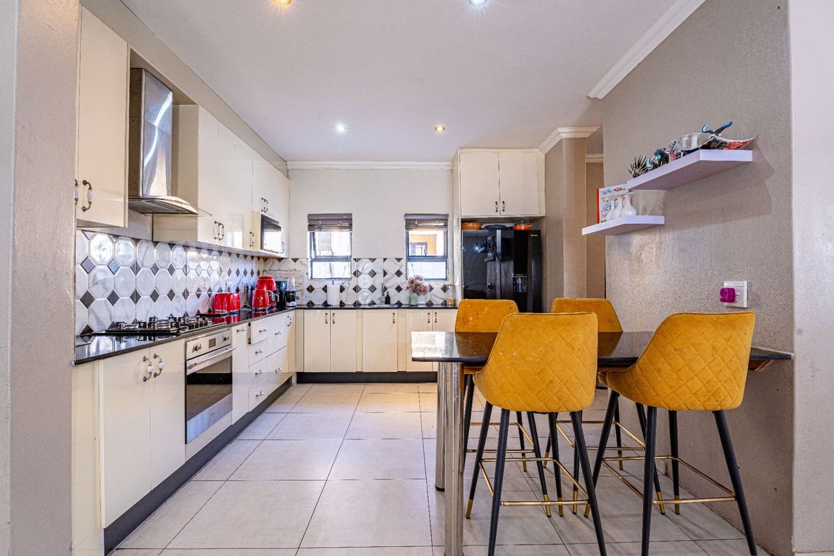 A well-maintained kitchen featuring modern cabinetry, a gas hob with extractor fan, tiled backsplash, and integrated appliances, offering a functional and clean cooking space.
