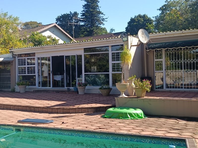 Rear exterior view featuring a swimming pool, paved patio area, and sliding glass doors providing access to the main dwelling.